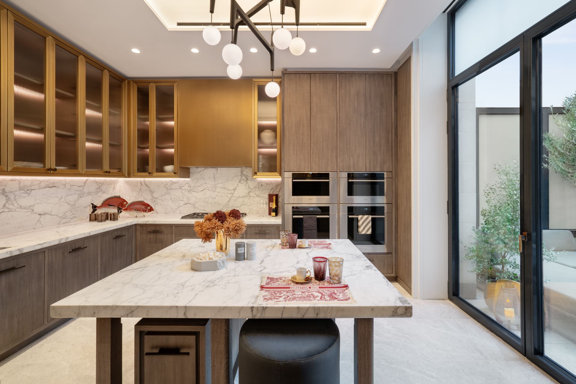 Kitchen with dark wooden cabinets, white marble countertops and gold cupboards.