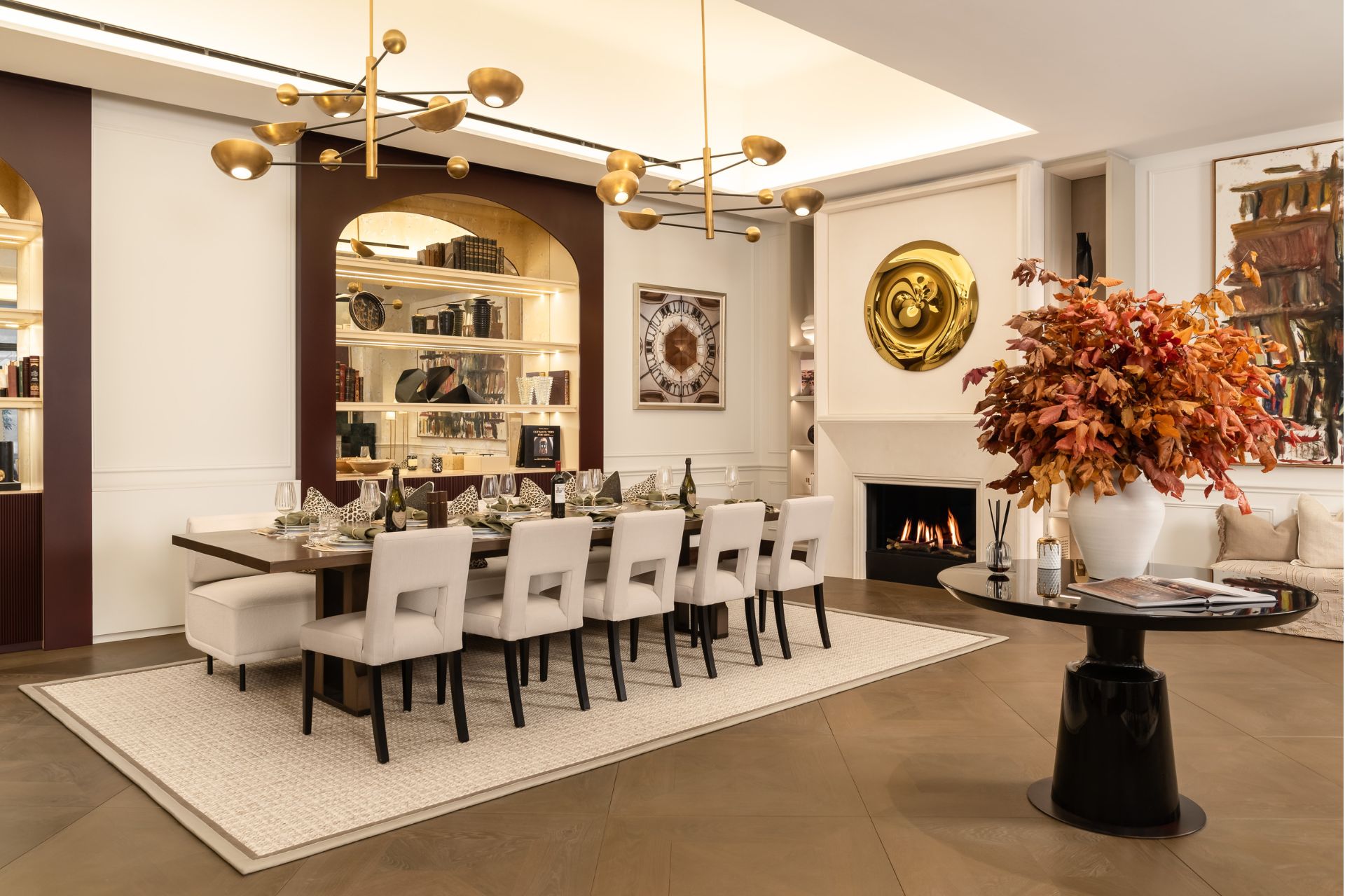 Dining area with cream rug and chairs, a glass table and a gold light fixture.