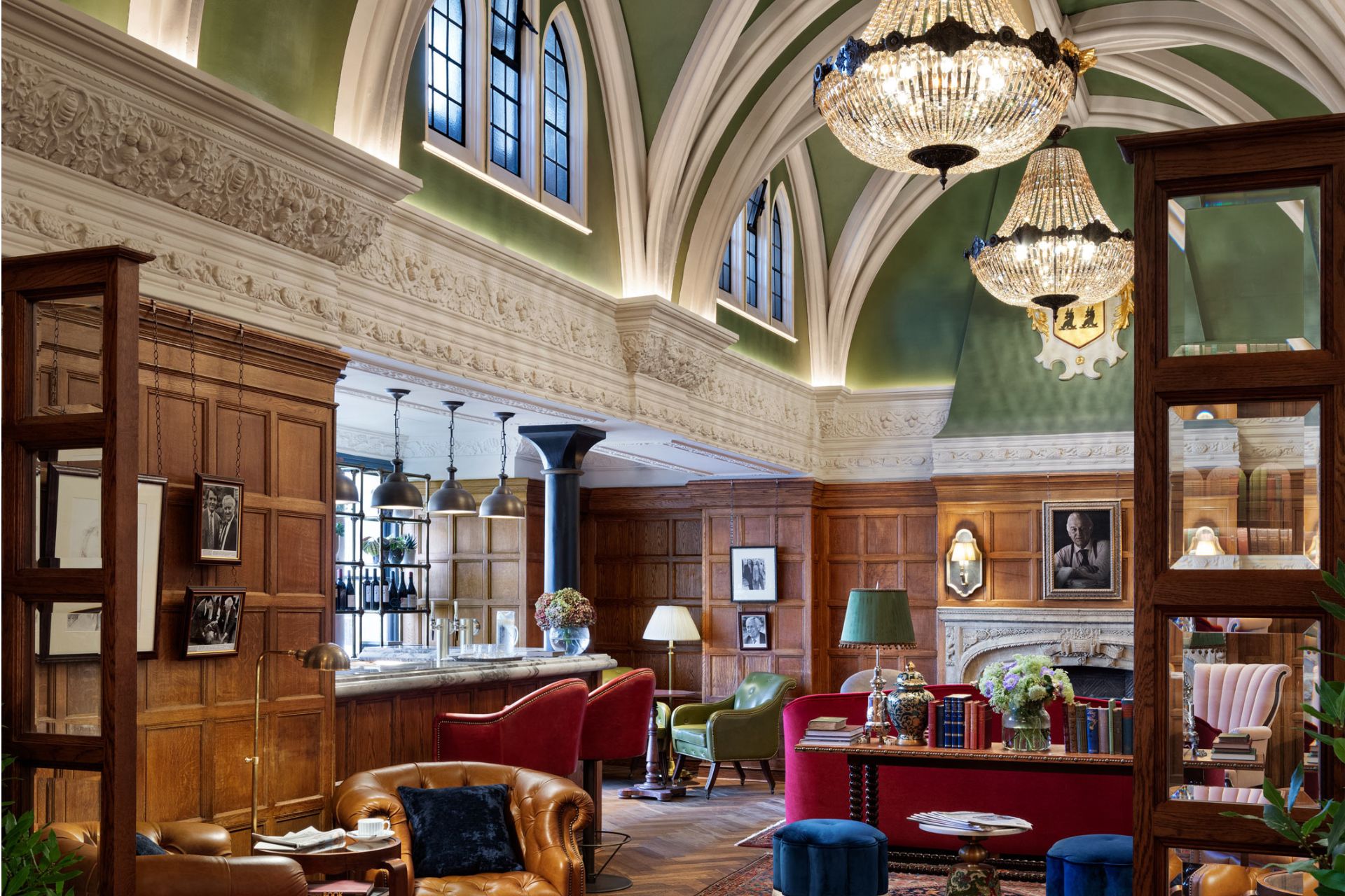 Bar with vaulted ceilings, leather and velvet seats and large chandeliers.