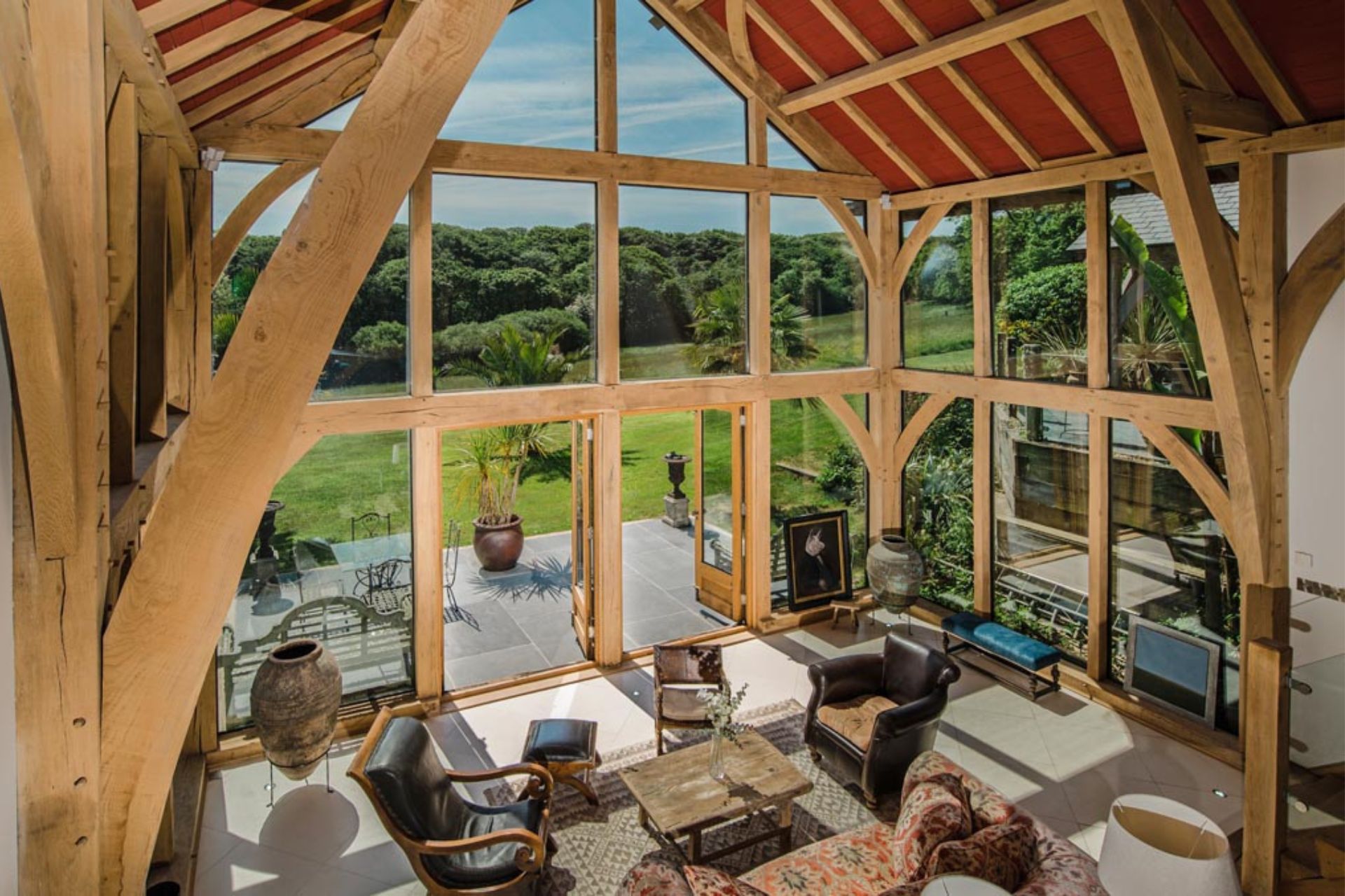 Wood-beamed living room with full-height glazing and views of the countryside.