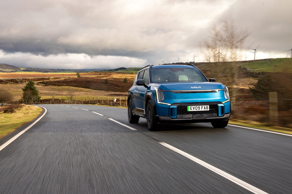 Blue Kia EV9 driving along a road