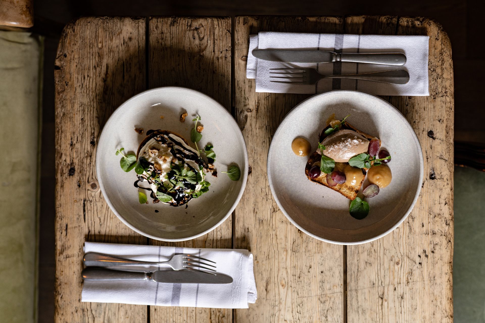 Two plates of roast dinner on a wooden table