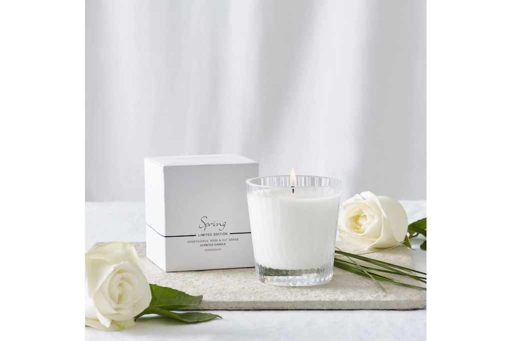 White candle next to white box with roses