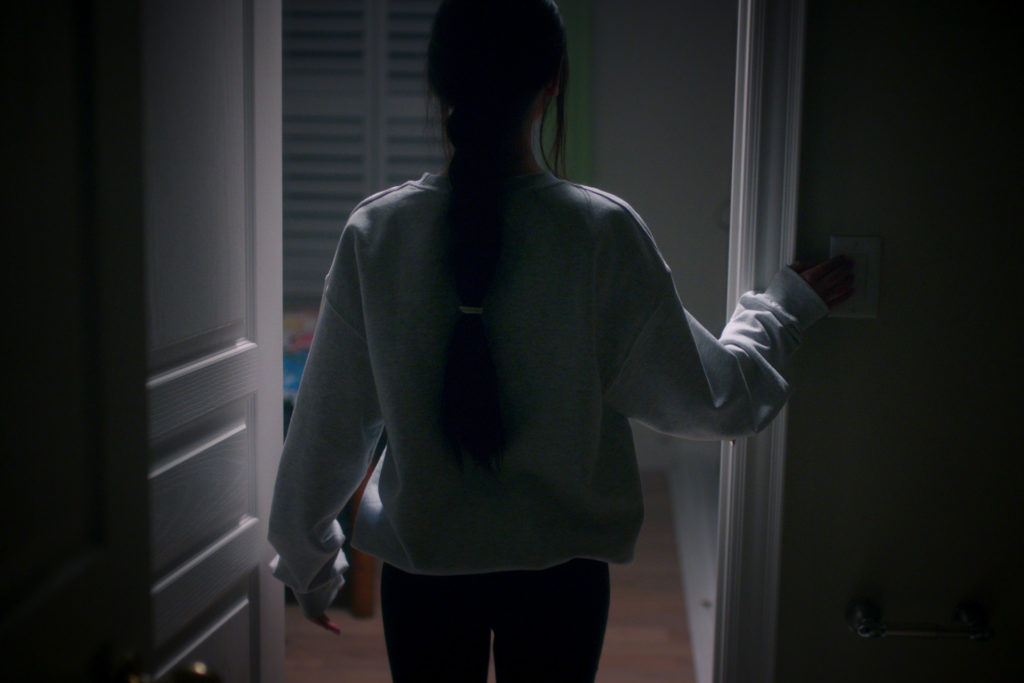 A still from What Jennifer Did showing the back of a woman entering a bedroom