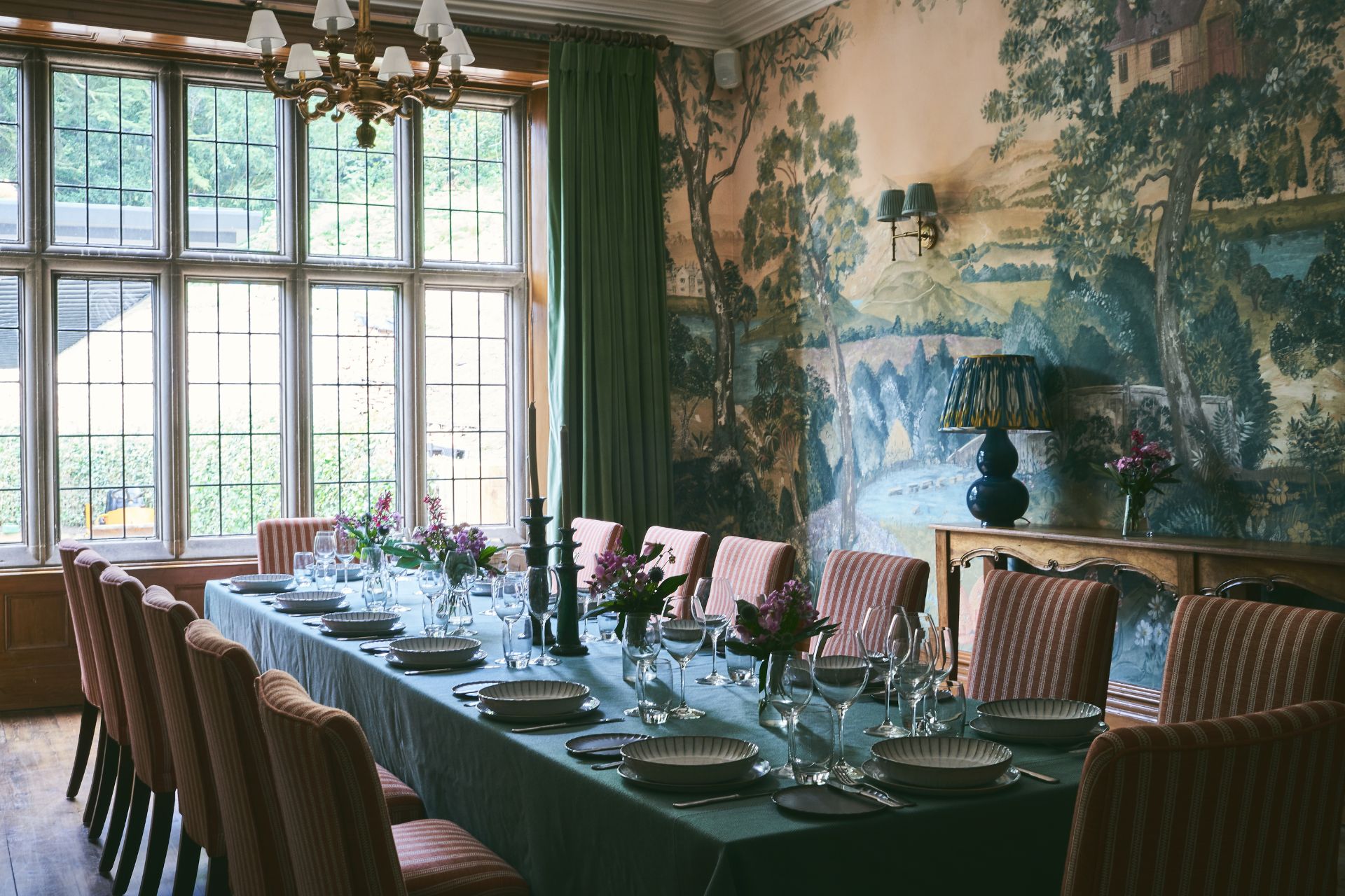 Dining room with long wooden table, red chairs and a chandelier.