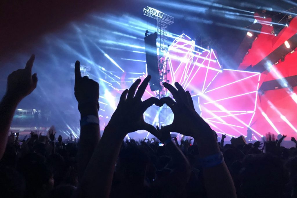Crowd making heart signs at a concert.