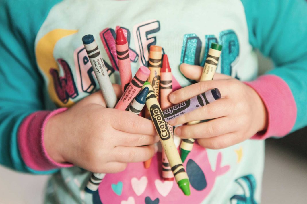 child with a handful of crayons