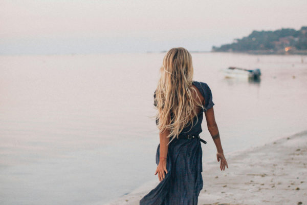 A blonde woman walking down the beach