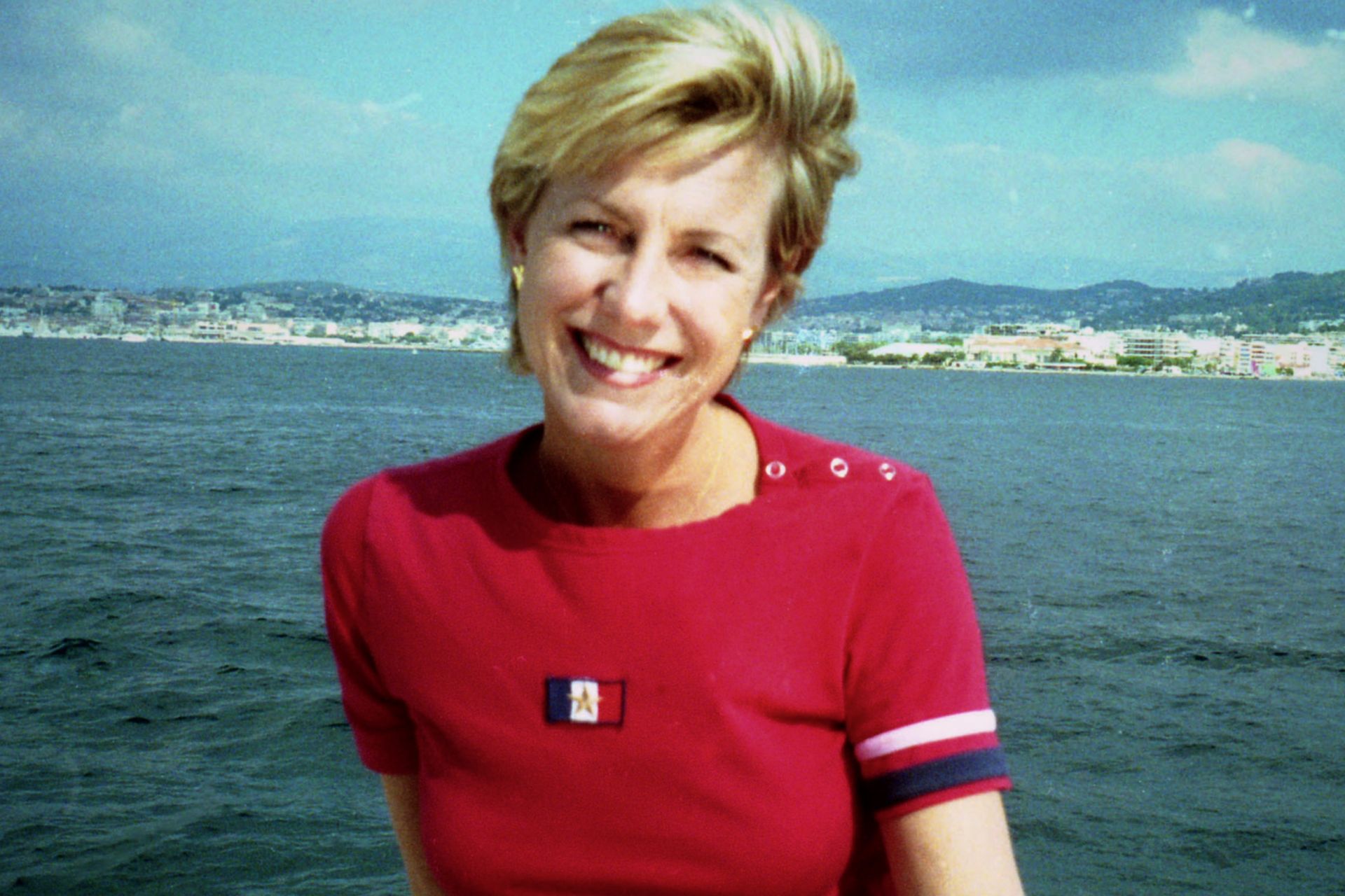 Jill Dando wearing a red Tommy Hilfiger t shirt, with the ocean in the background.