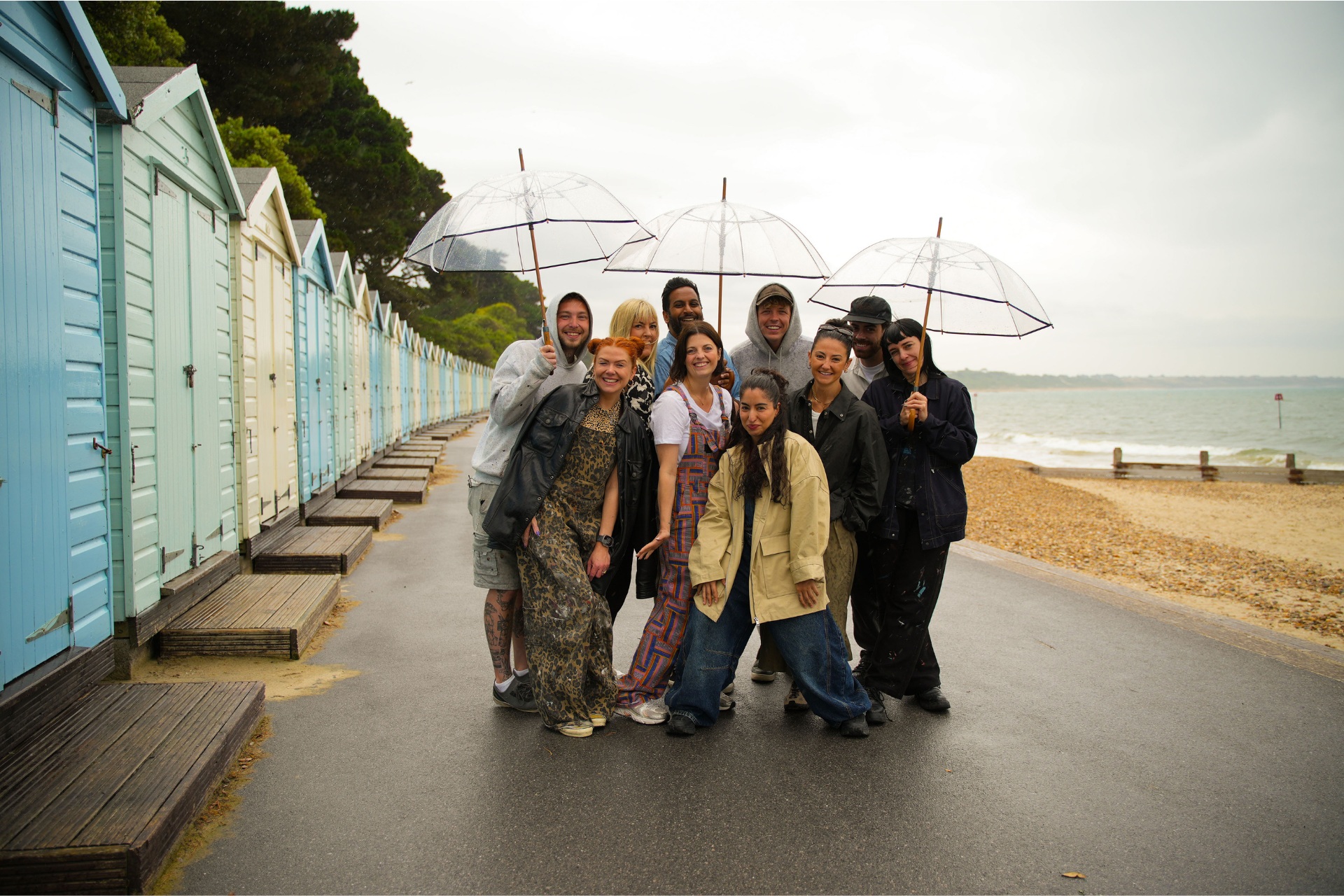People in the rain by the sea, holding umbrella
