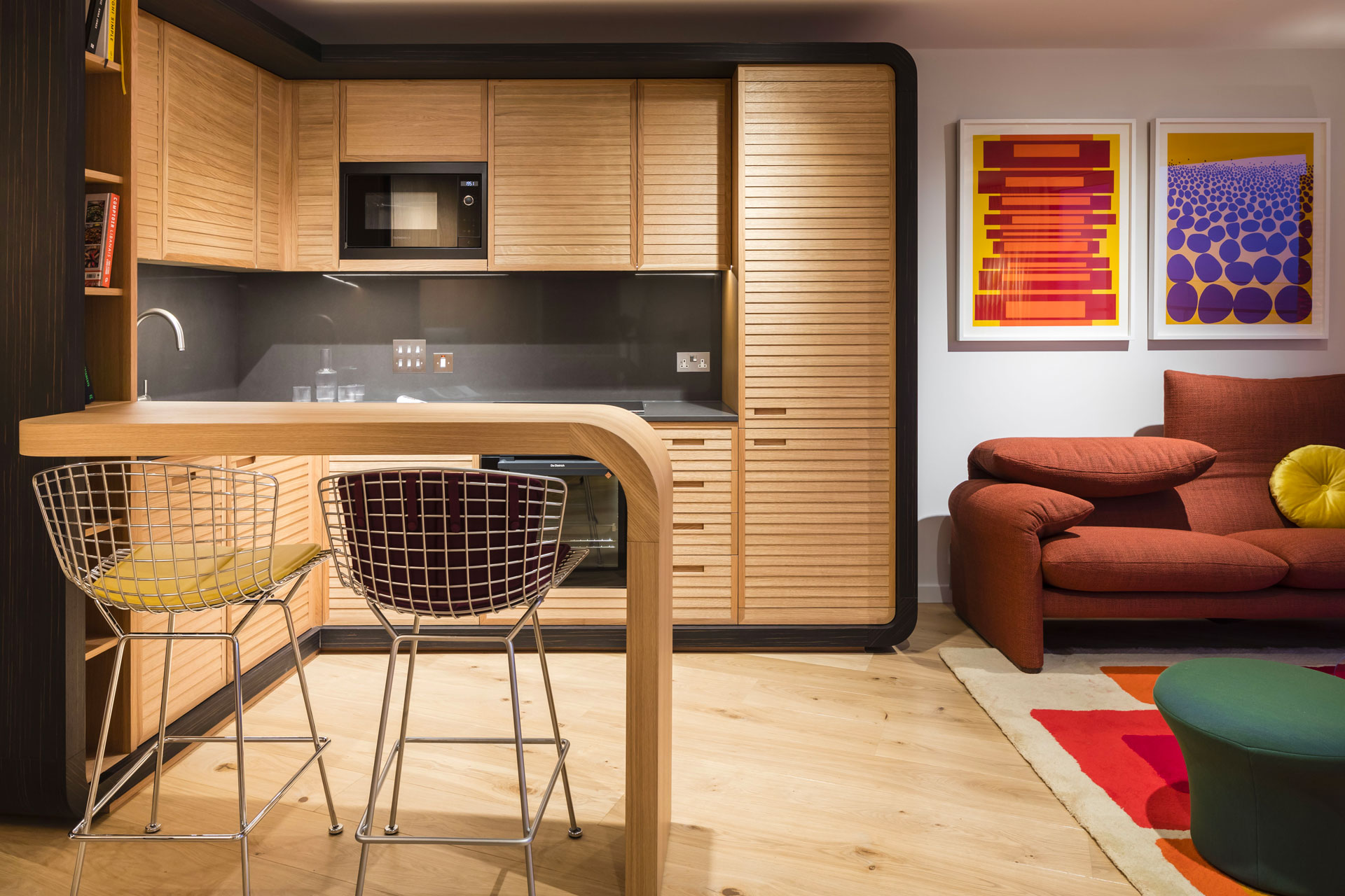 An oak veneer kitchen with a curved breakfast bar and two high seating stools