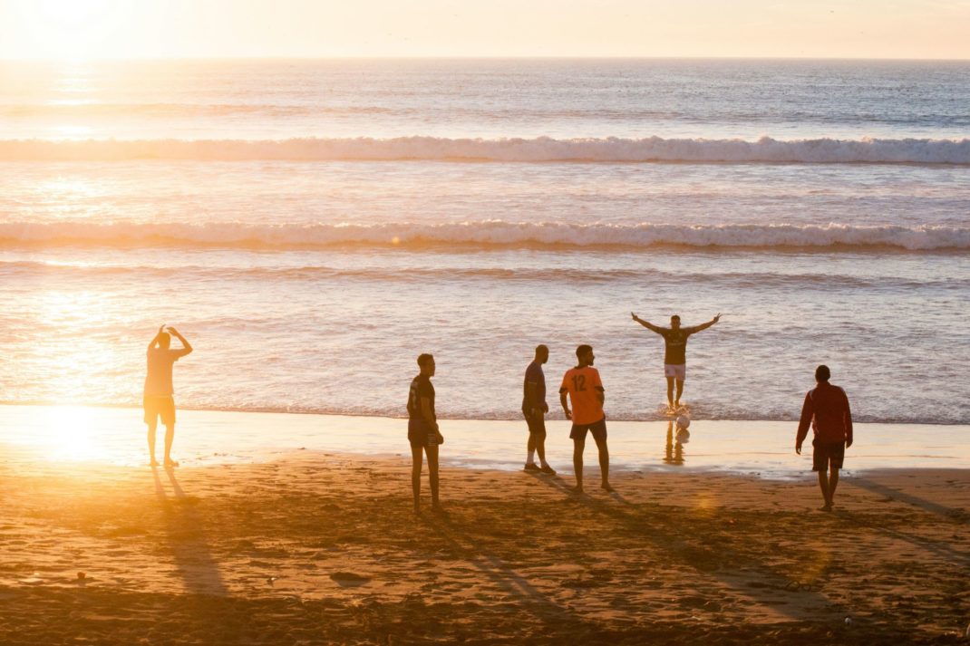People playing on the beach at sunset.