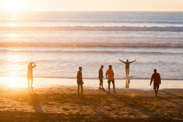 People playing on the beach at sunset.