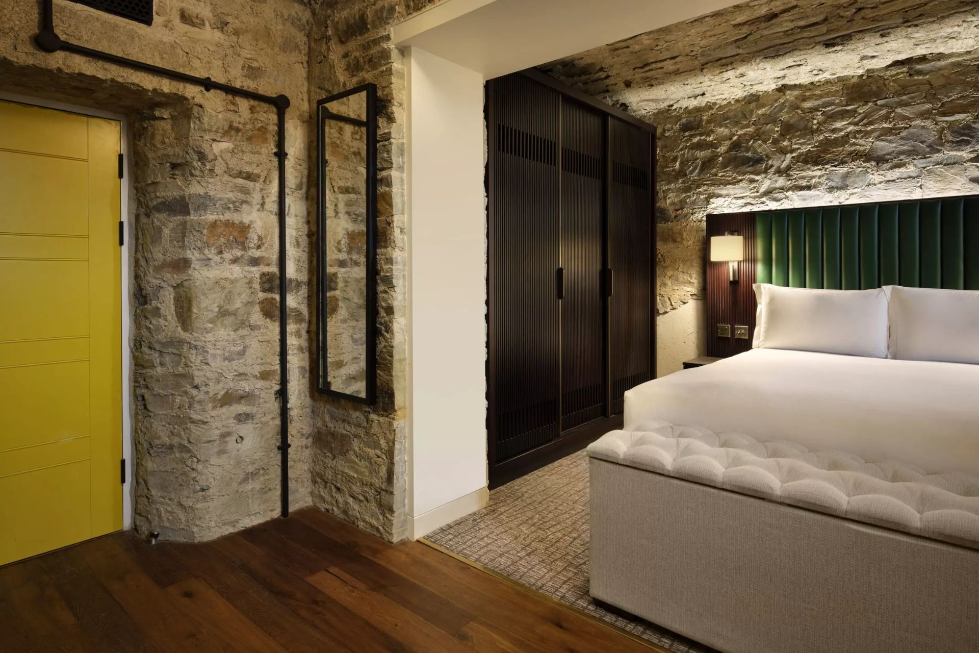 Hotel room with stone walls and a yellow door
