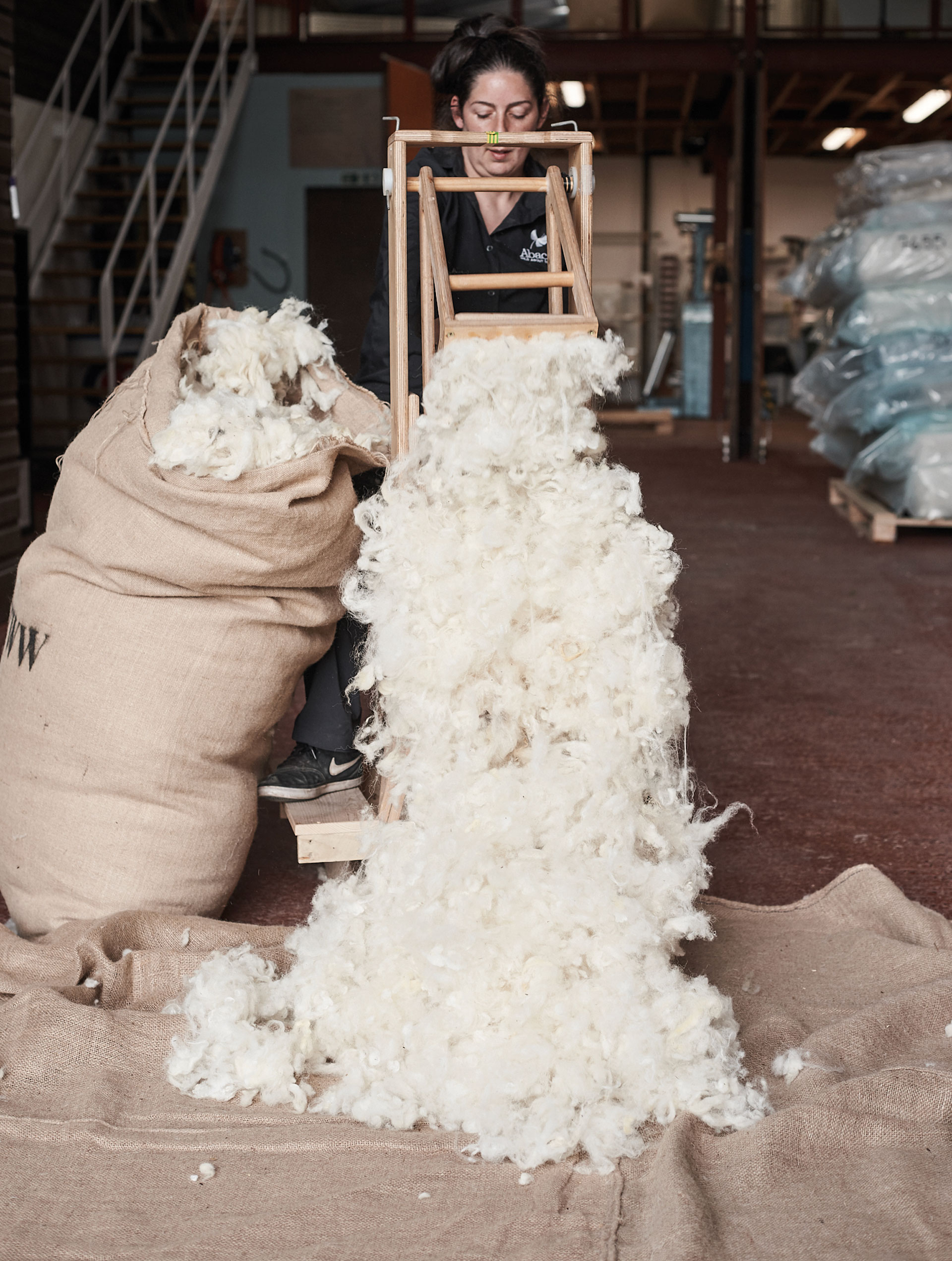A woman tips a bag of wool open