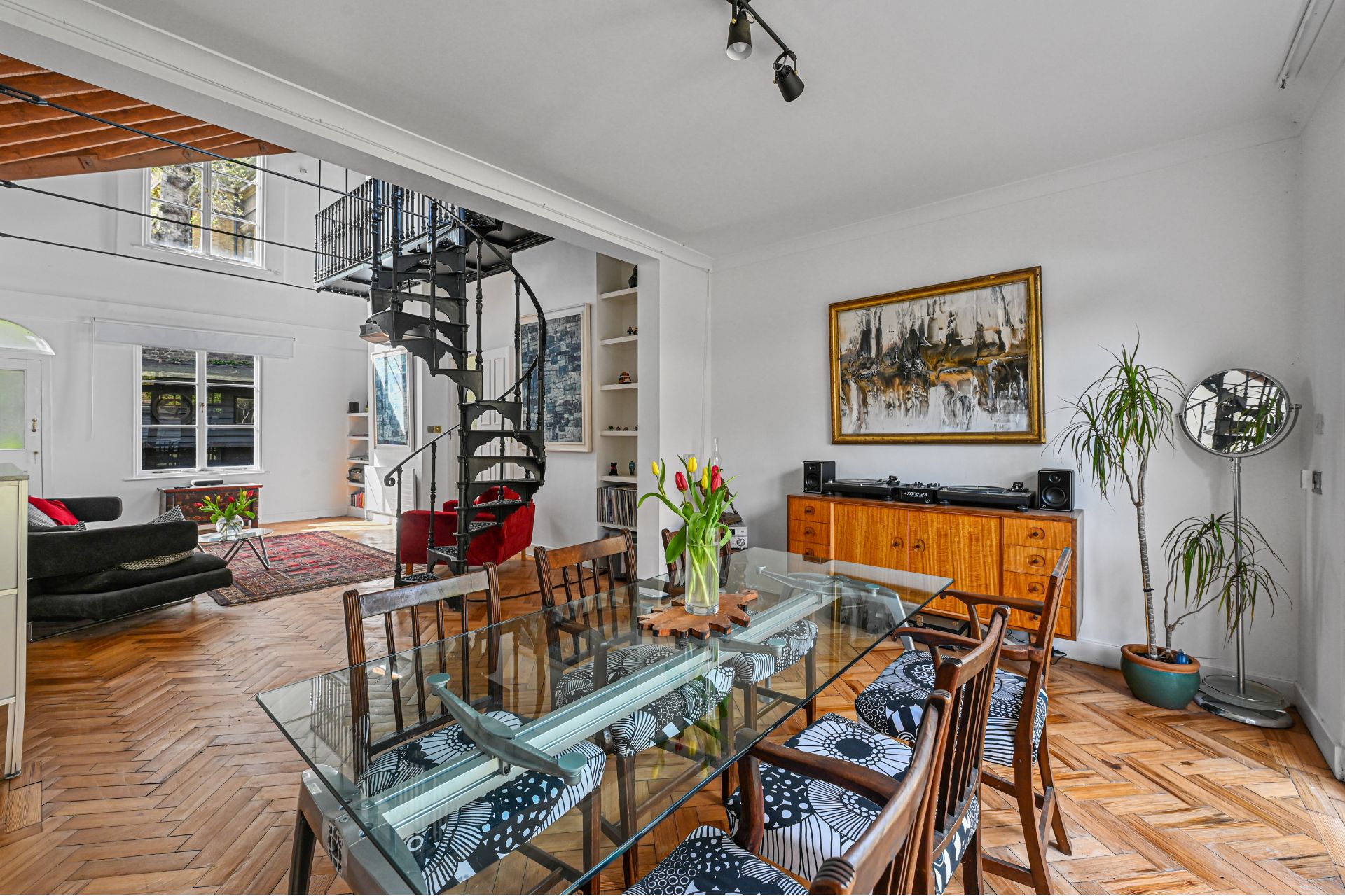 Dining room with parquet floors, glass table and wooden chairs.