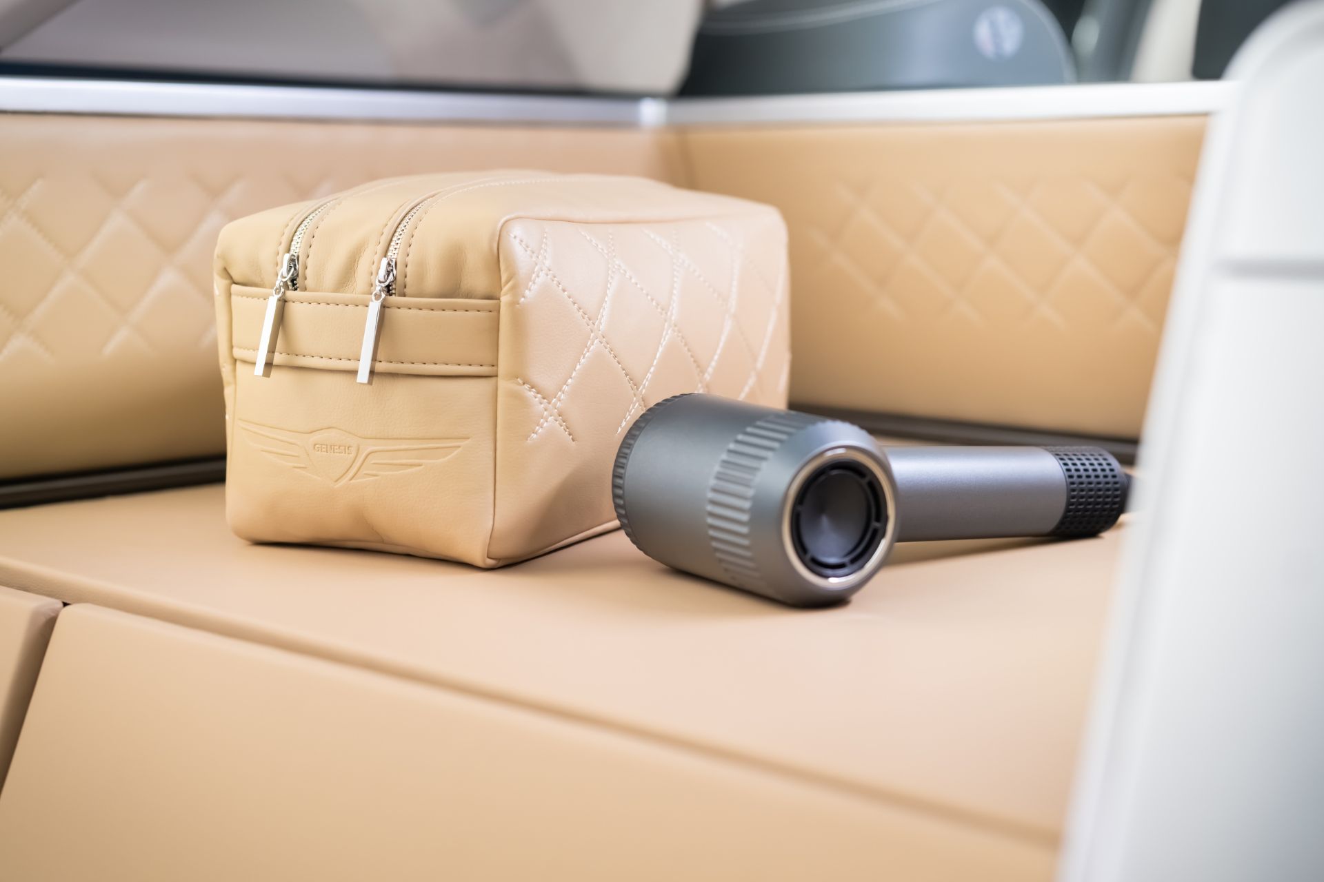 Cream-coloured dog bed with matching pouch and a hairdryer beside.