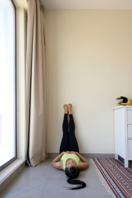 Woman lying with her feet up against a wall