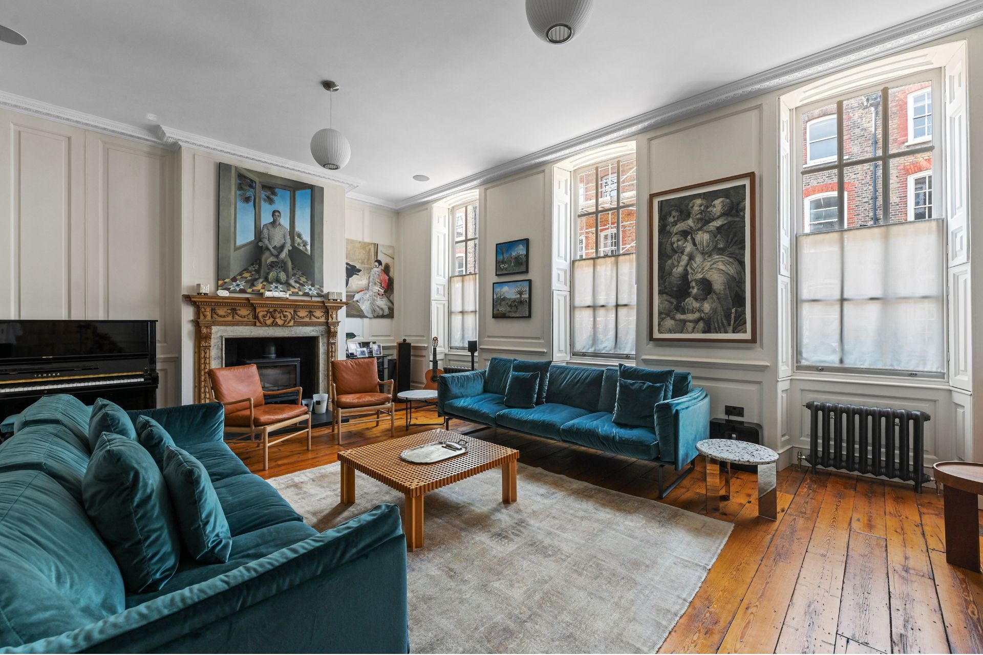 Living room with wood floor, sash windows and a green velvet sofa.
