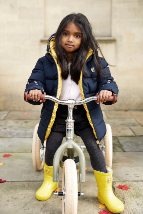 Little girl on bike wearing yellow wellies | country kidswear
