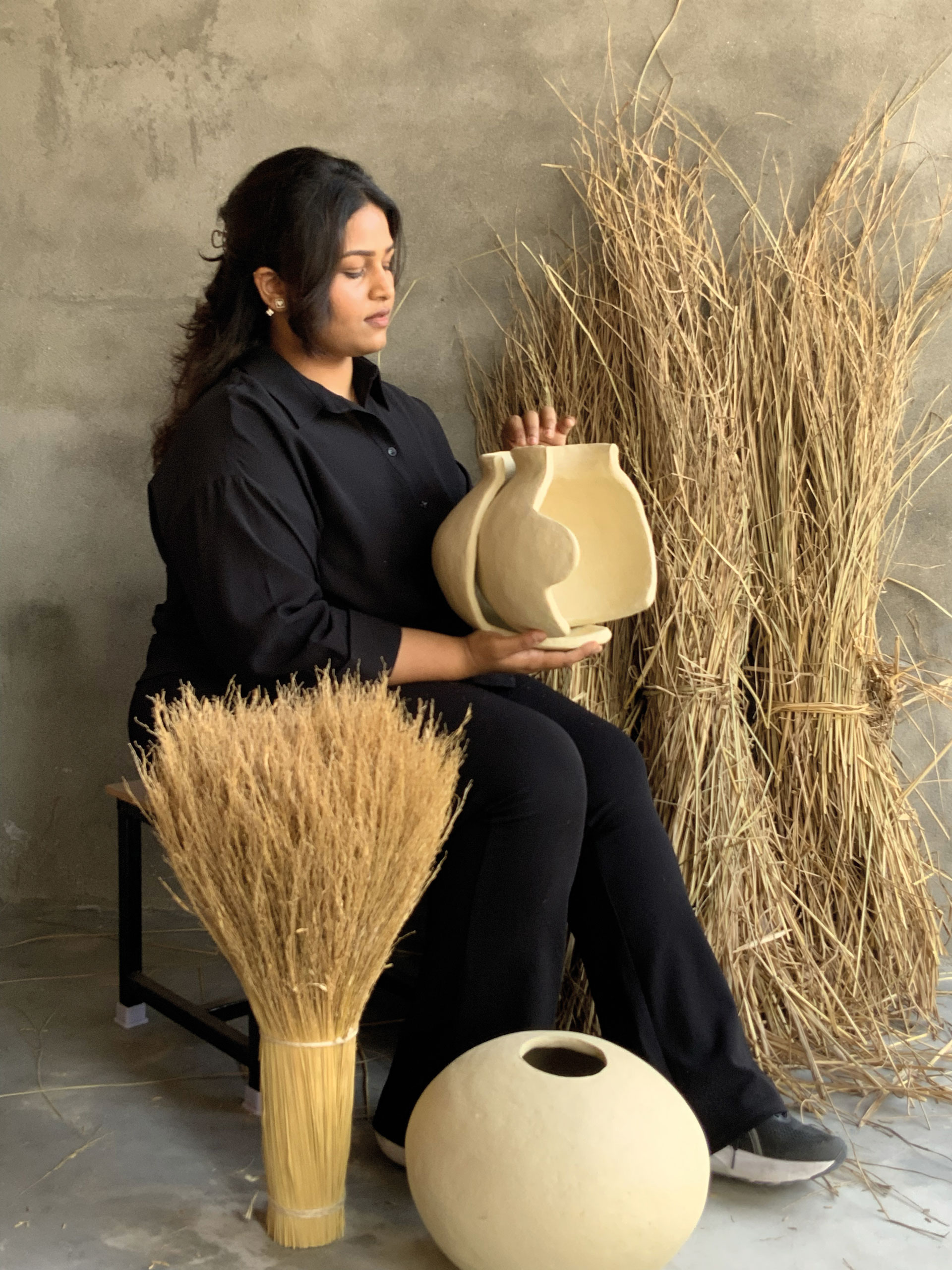 An Indian artisan holds a pot surrounded by Rice Straw