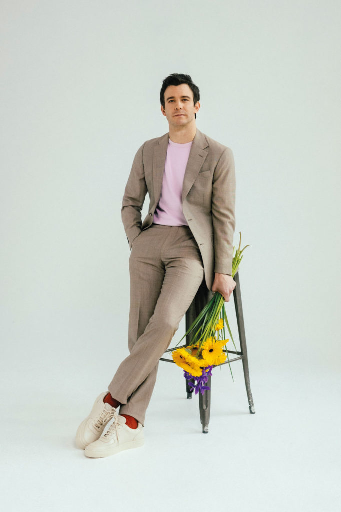 Luke Thompson with a bunch of flowers, leaning against a stool