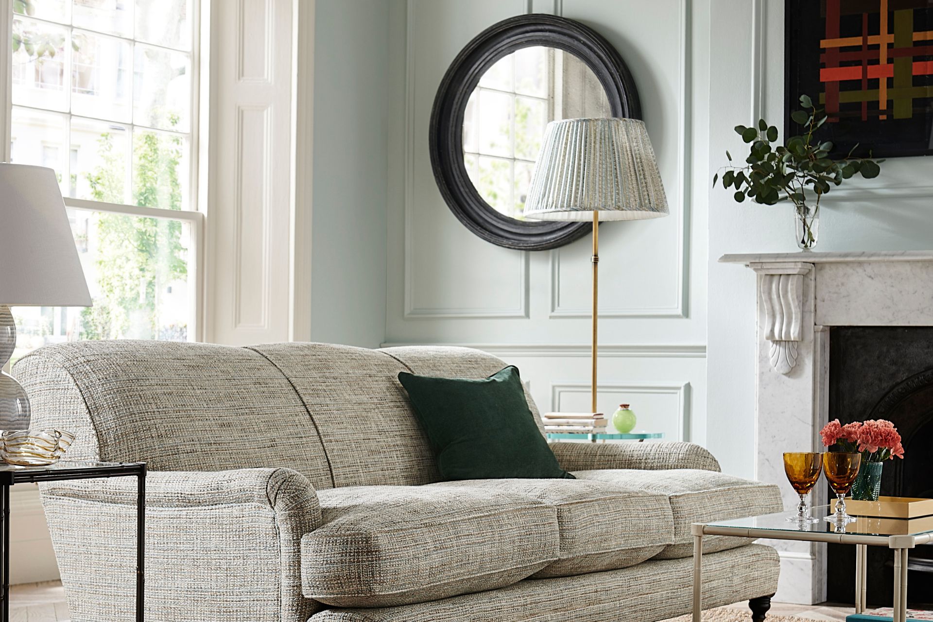 Living room with light grey sofa, dark blue cushions and off-white panelled walls.