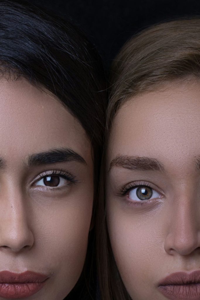 Two women photographed against a black background