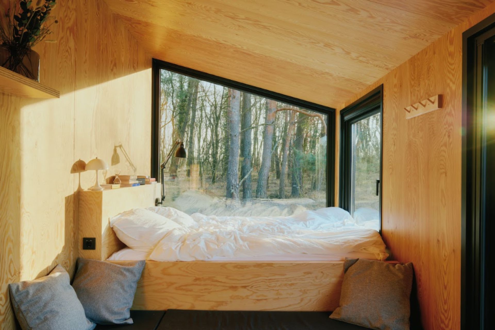 Bed in wooden cabin with floor-to-ceiling windows