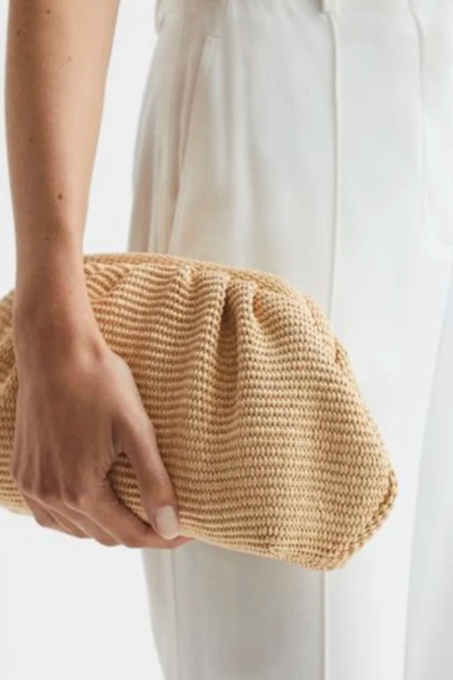 Close up of hand holding clutch raffia bag
