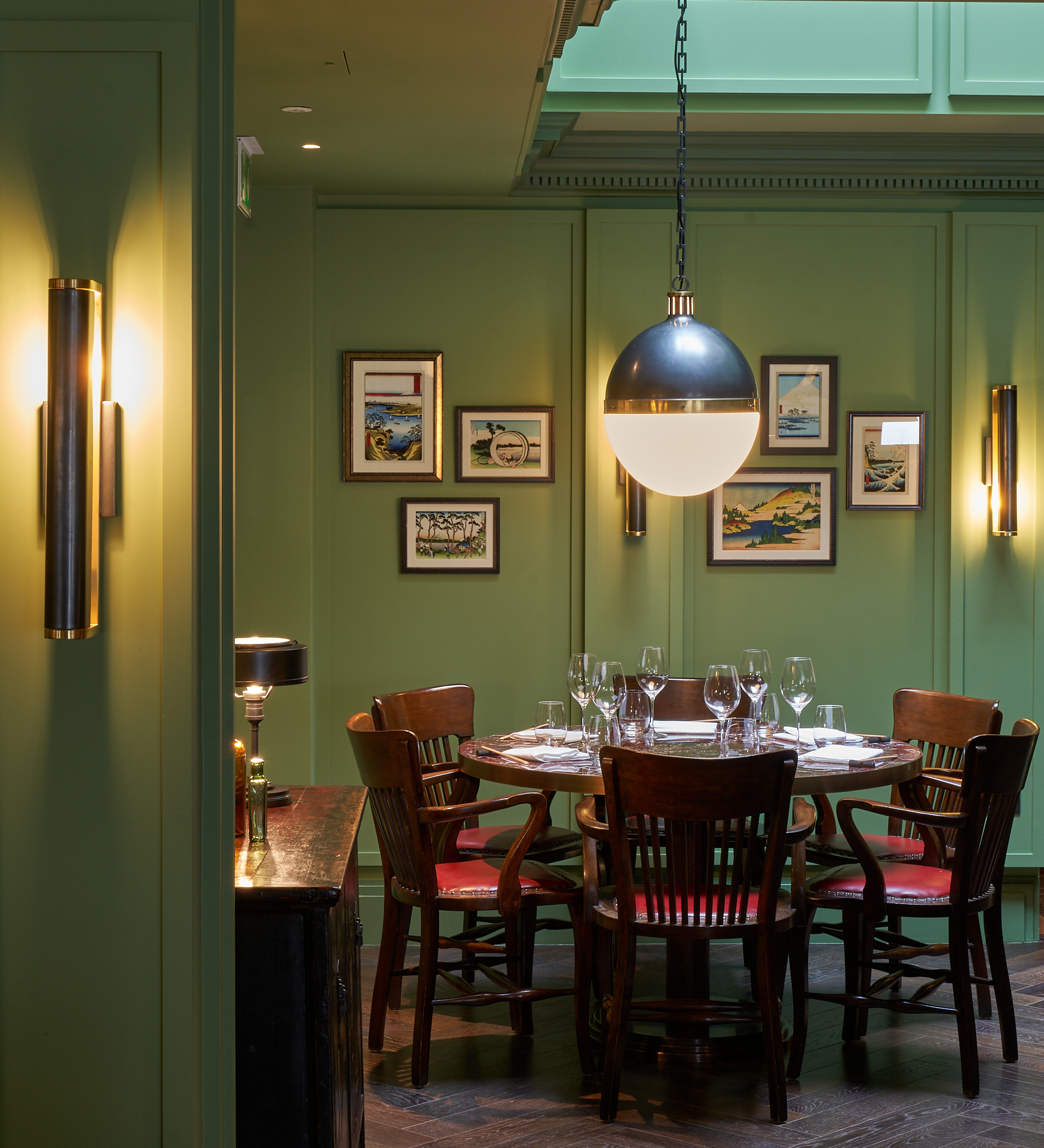 The Fuji Grill restaurant, with sage green walls, dark wooden chairs and a spherical light fixture.
