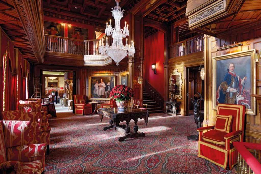 Drawing room with red panelled walls, velvet curtins and a crystal chandelier