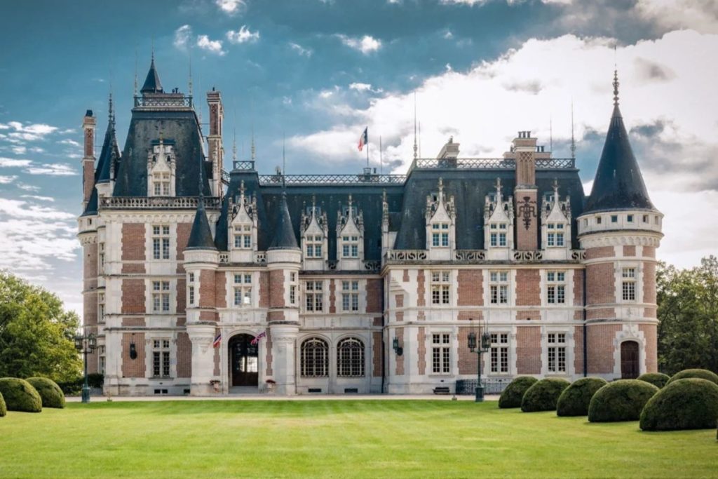 Neo-Gothic-style chateau with brick towers and blue turrets.