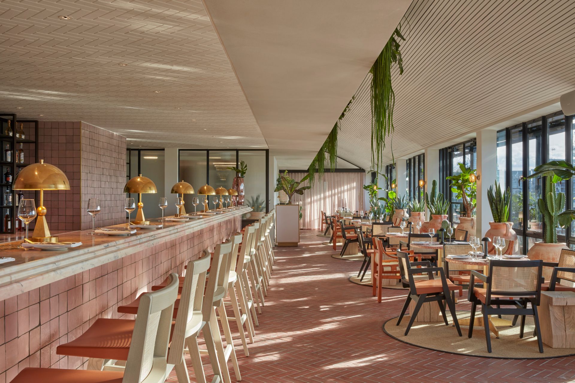 Rooftop bar with light pink tiles, rattan chairs and hanging foilage.