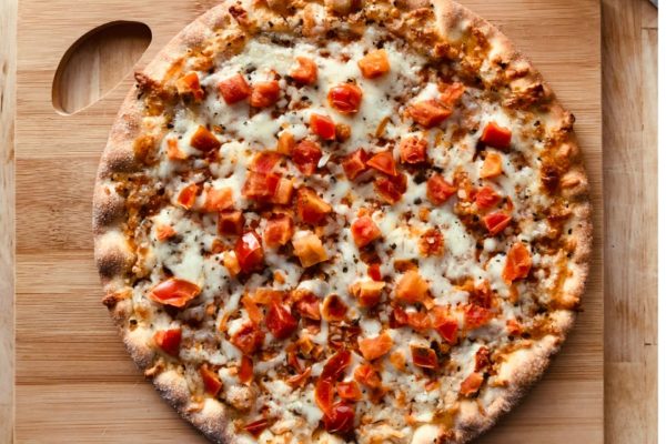 Aerial photo of vegetable pizza on wooden chopping board