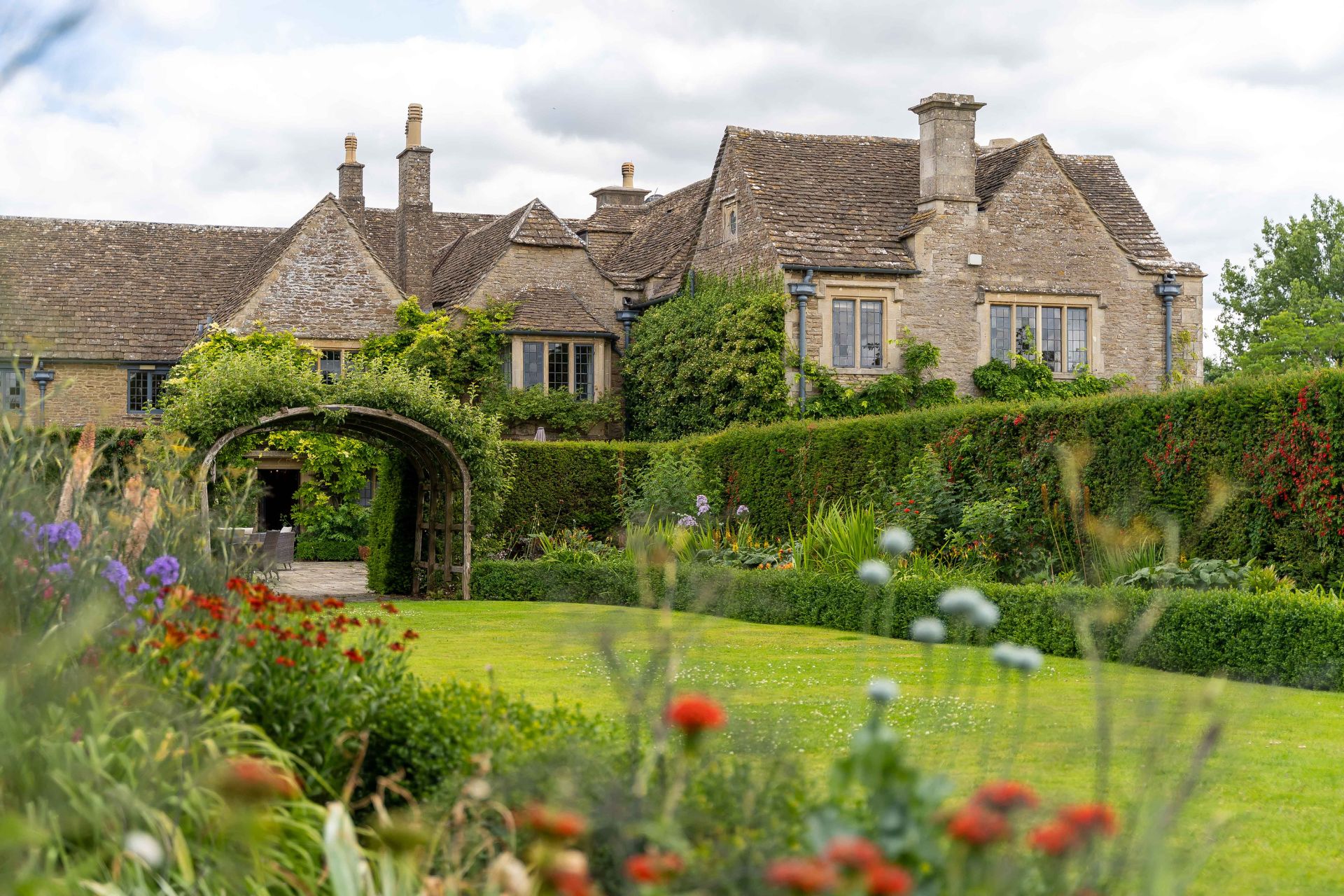Exterior of Whatley Manor, featuring a stone archway and landscaped gardens.