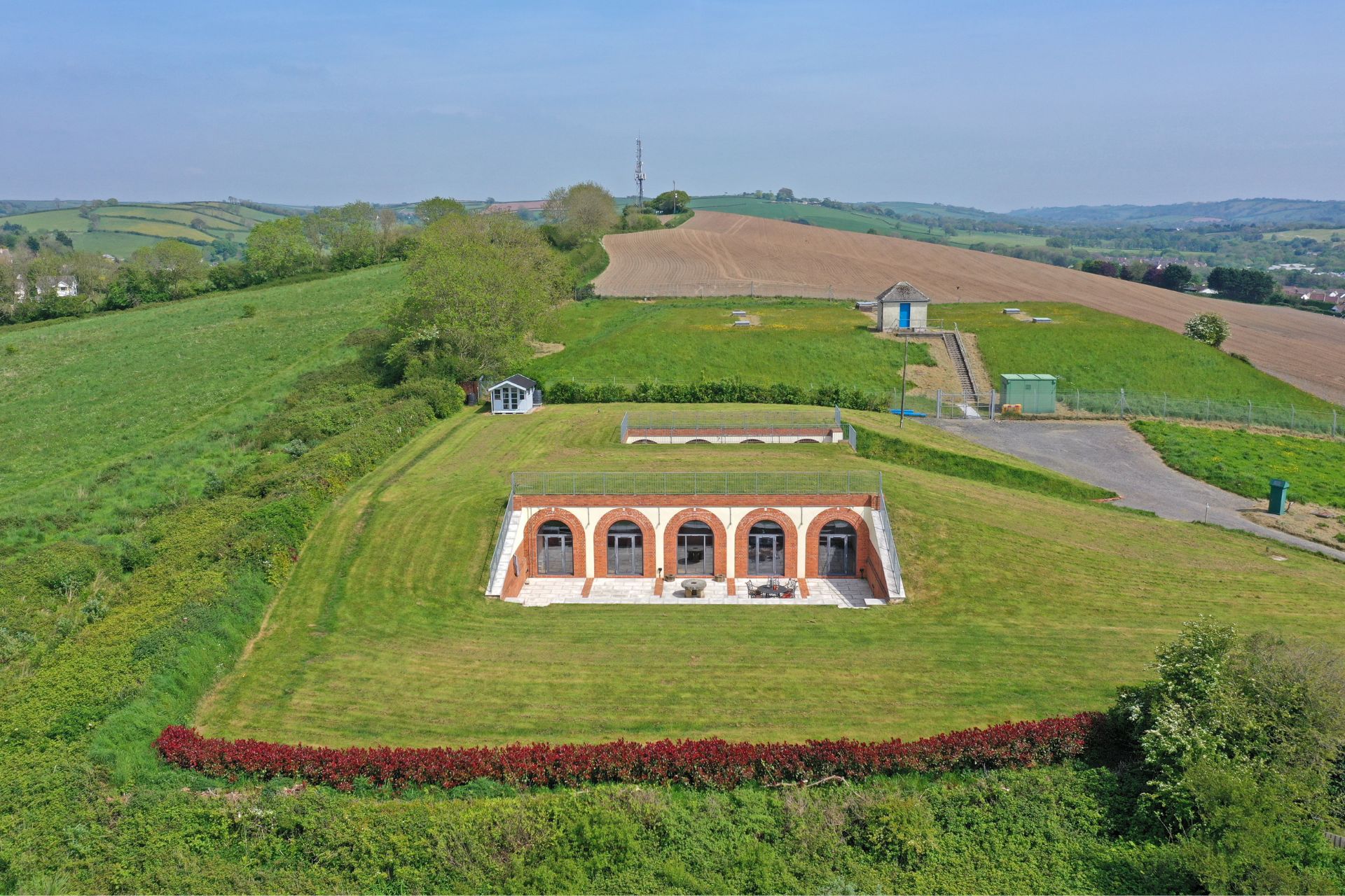 Aerial view of a subterranean home with red brick arches around the windows.