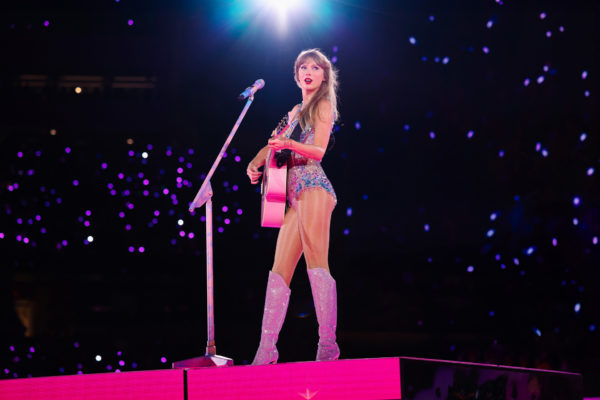 Swift with a guitar performing at The Eras Tour