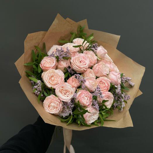 A bunch of pink flowers wrapped in brown paper
