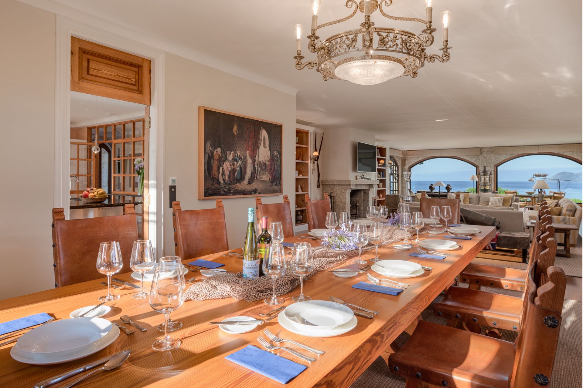 Dining room with long wooden table, mosaic chandelier and a view of the mountains.