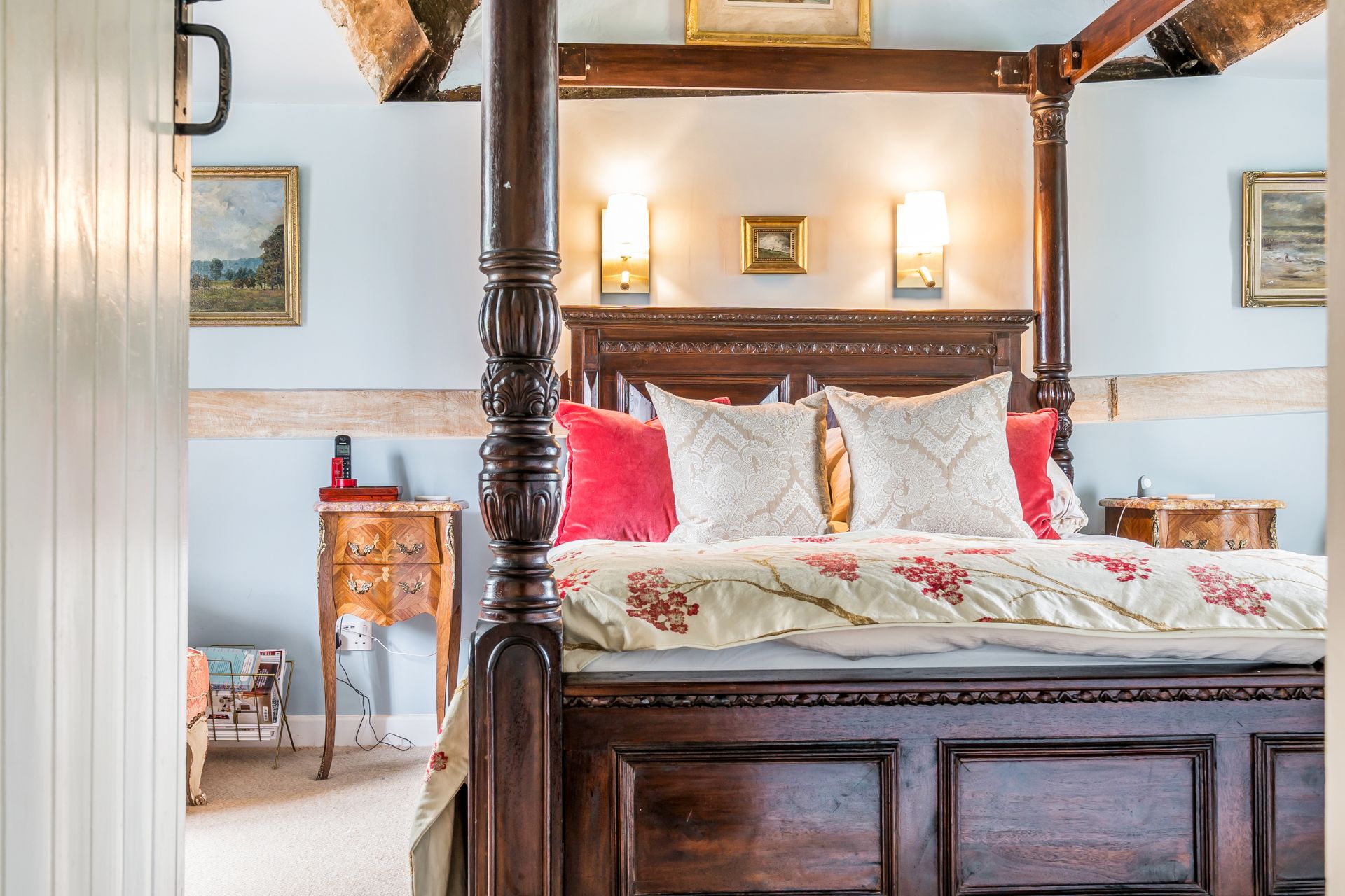 Bedroom with pale blue walls and a dark wooden four-poster bed.