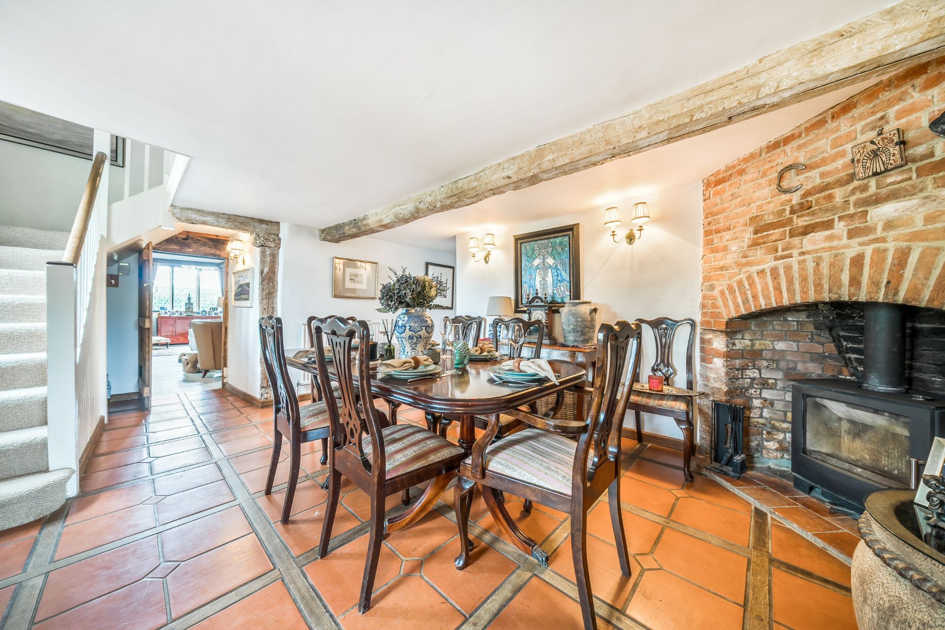 Dining room with flagstone floors, a brick fireplace and wooden furniture.