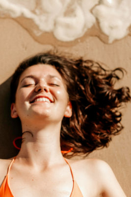 Woman laying on sandy with beachy bob