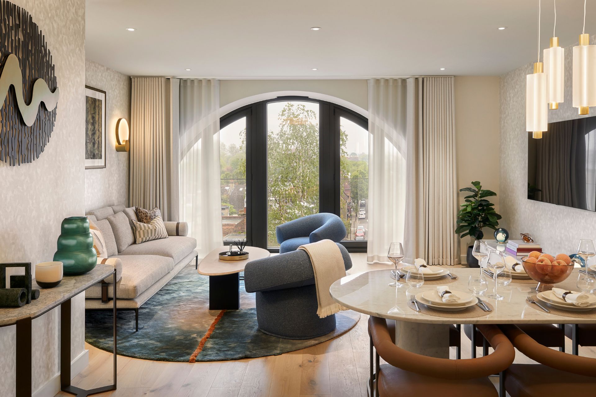 Living room with curved navy sofa, round dining table and circular window.