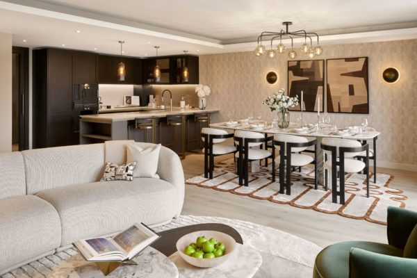 Living room with curved boucle sofa, white dining table and black kitchen cabinets.