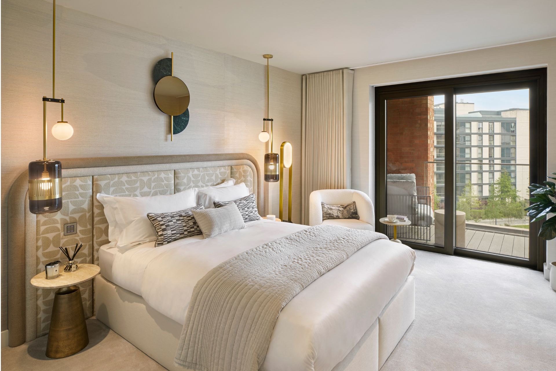 Bedroom with geometric print headboard and taupe bedspread, with sliding doors leading out onto a terrace.