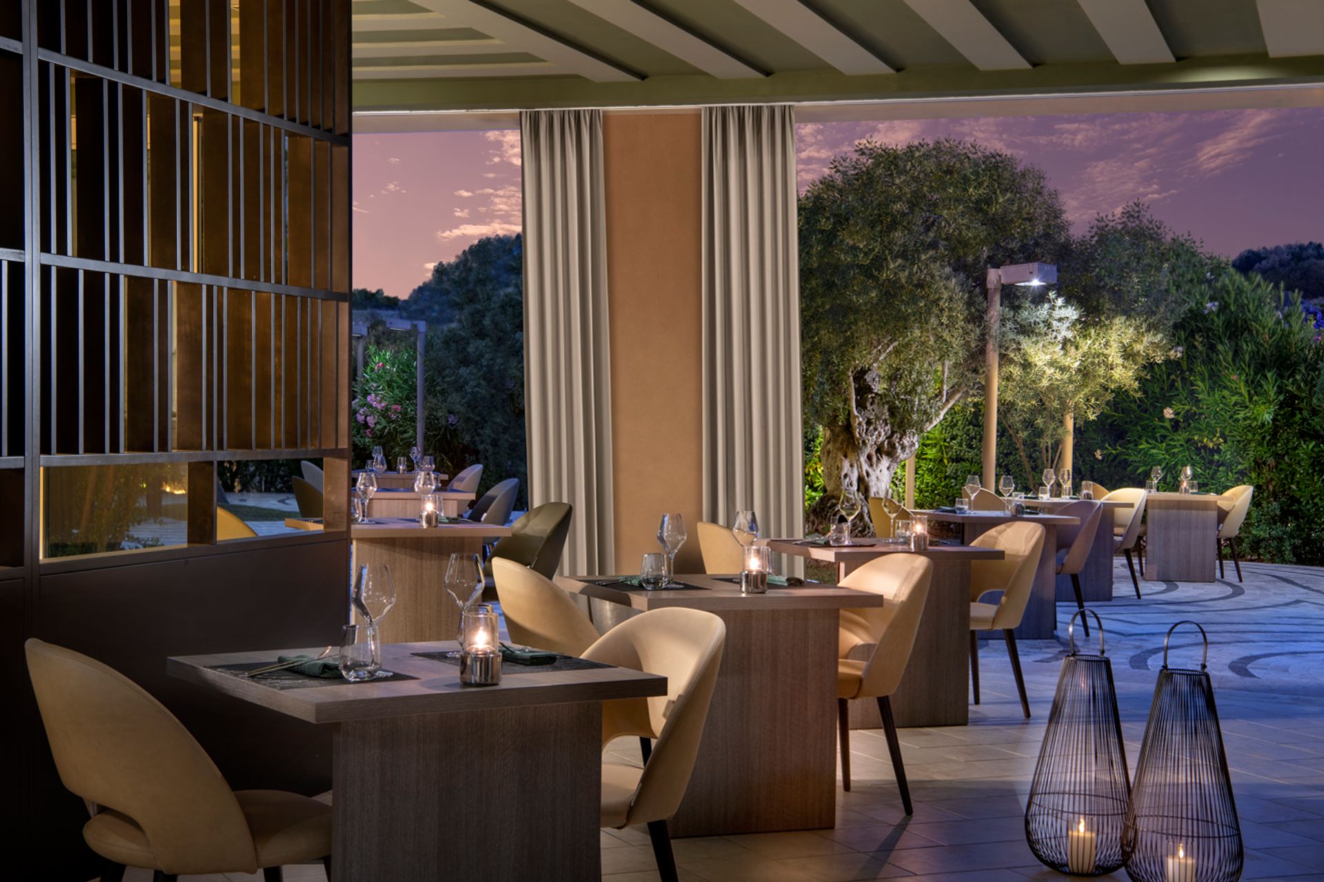 Restaurant with lanterns, wooden tables and a view of the Sardinian mountains, photographed at dusk.