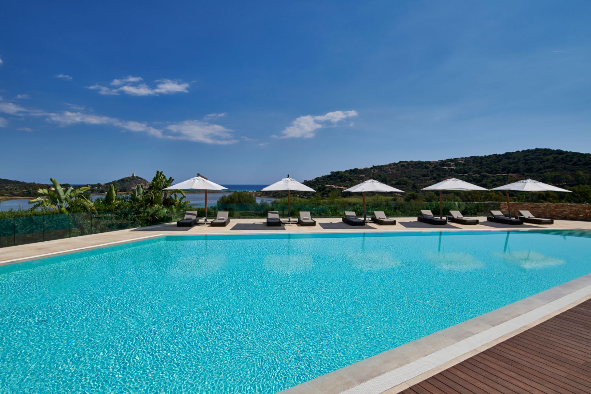 Pool with sun loungers, parasols and a view of the Sardinian mountains.