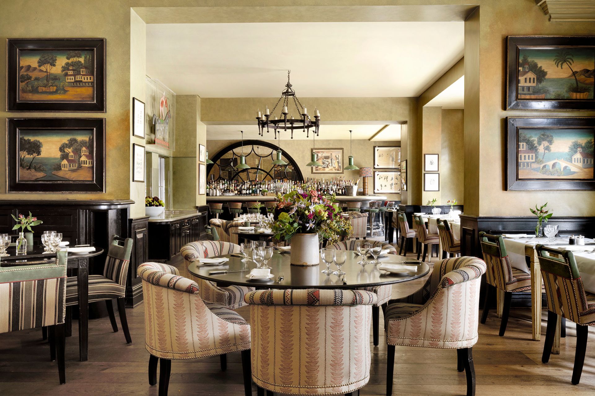 Brasserie with dark wooden tables, striped armchairs and chandeliers.