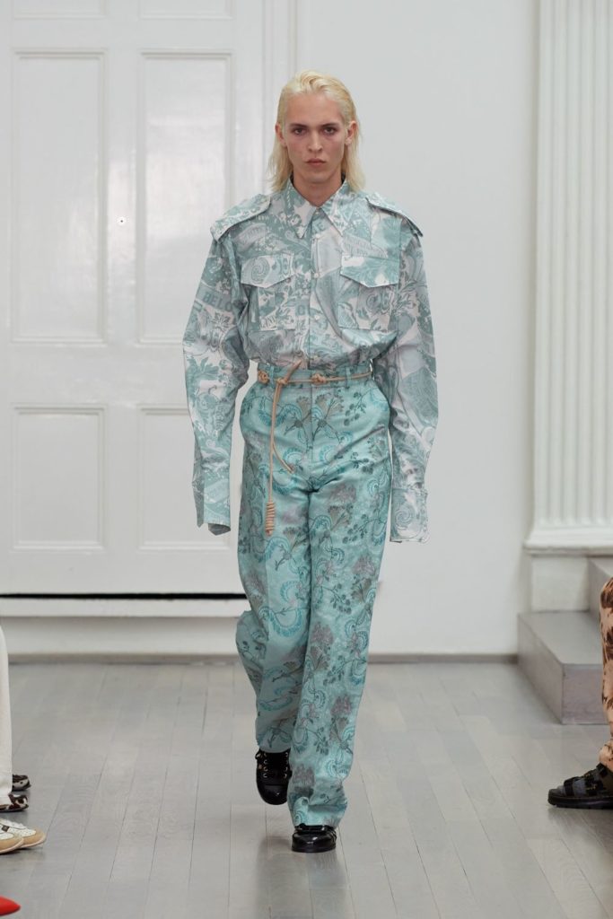 Model wearing blue and white trousers with matching utility-style shirt and black shoes.